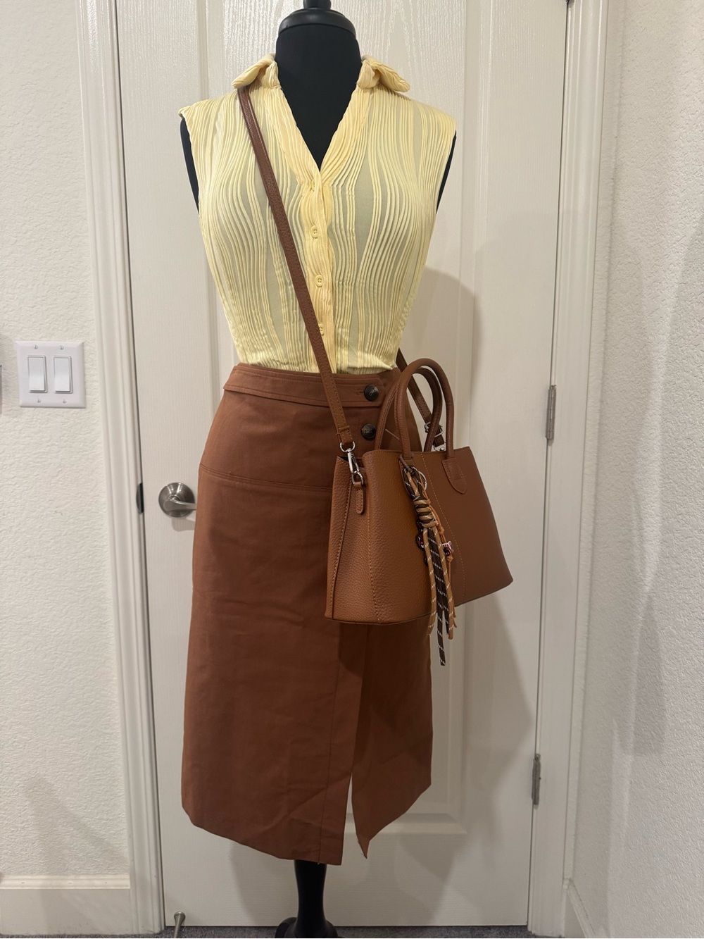 Sleeveless top, brown midi skirt and crossbody hand bag.